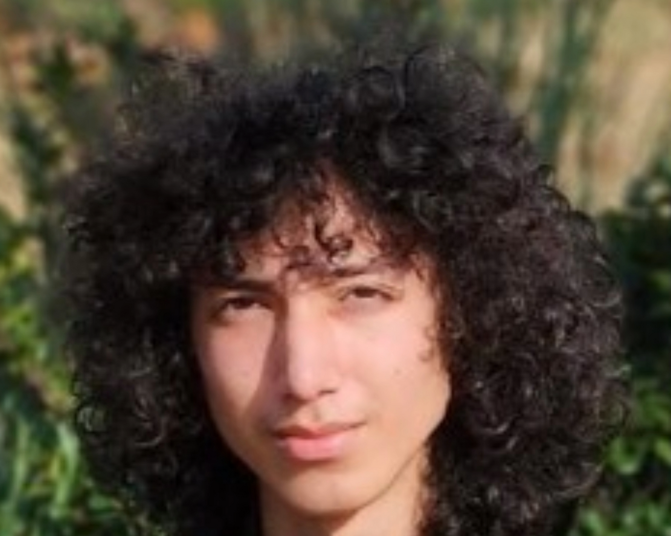 Person with curly hair in a natural outdoor setting